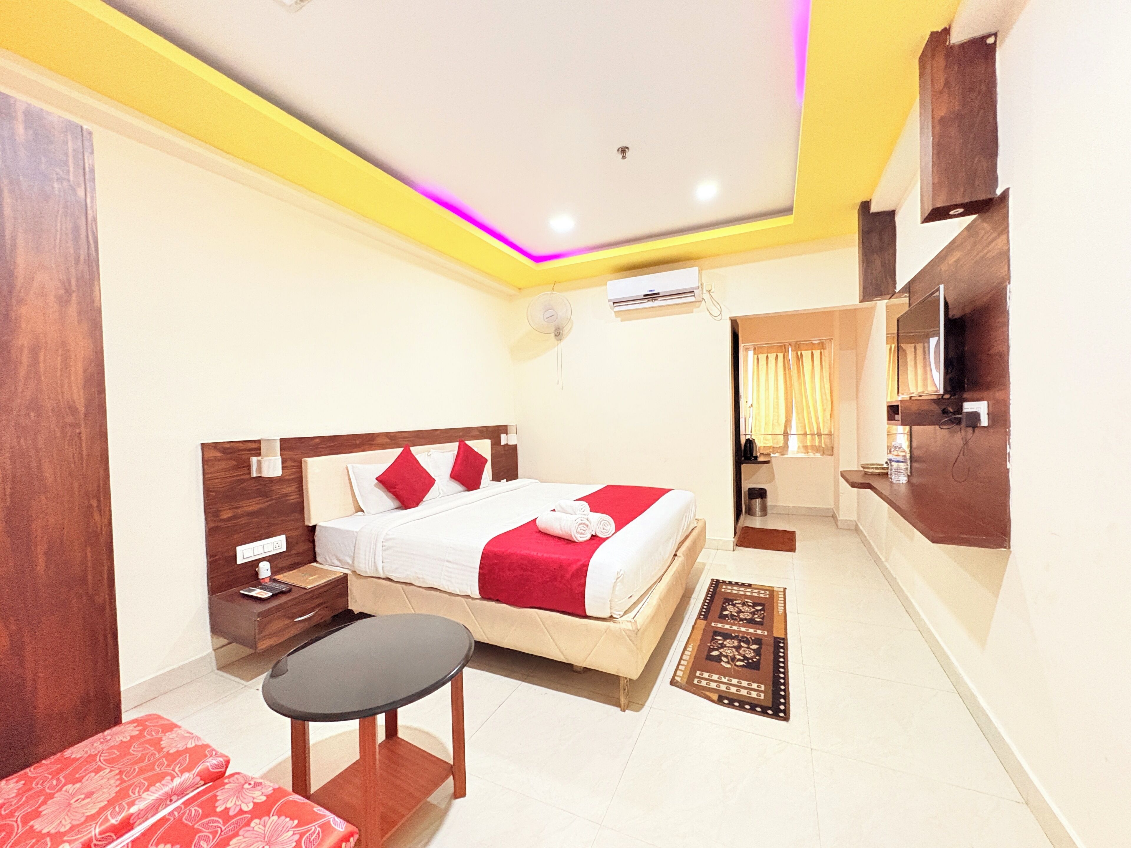 A hotel room with a bed, bedside table, and a small table.