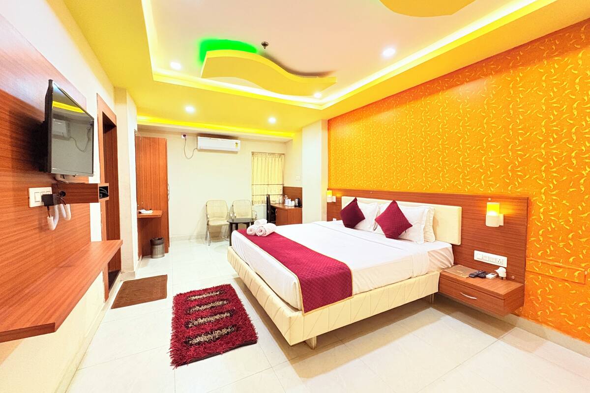 A hotel room with a large bed, bedside tables, a TV, and a desk.