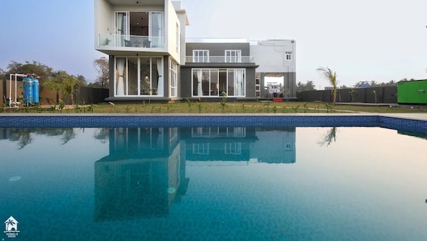 A modern two-story house with a swimming pool in front. - Suruchi Villa By Soumils Stays (Alibag)