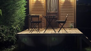En stuga av trä med en veranda, två stolar och ett bord.