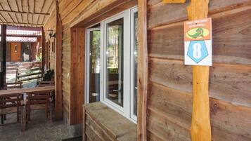 A wooden cabin with a stone bench and a wooden table.