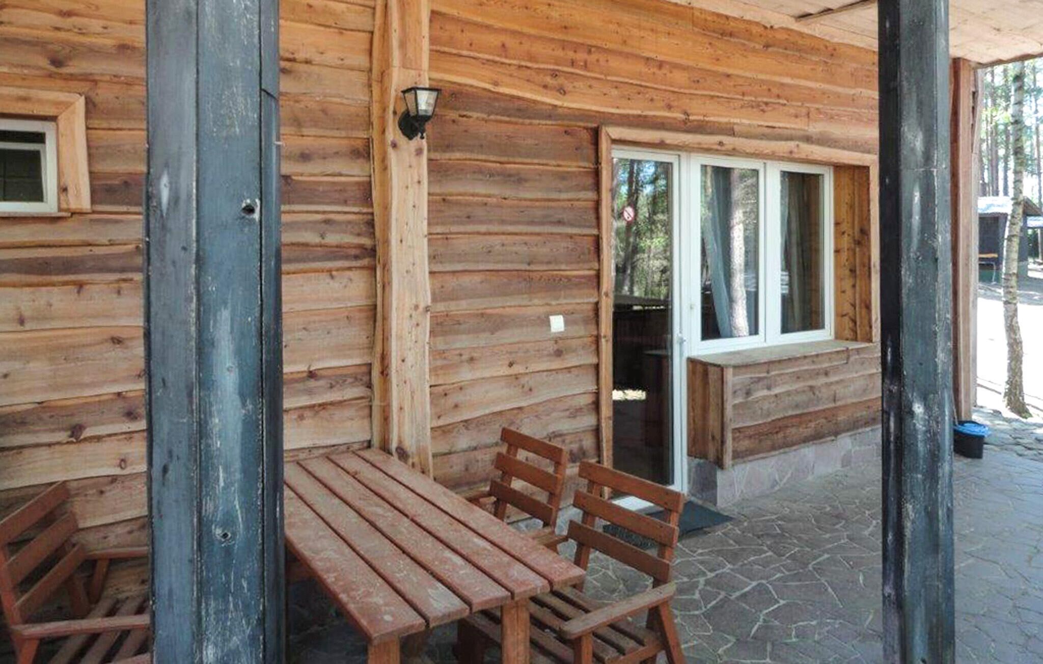 A wooden cabin with a stone-paved patio, a wooden table, and two chairs.