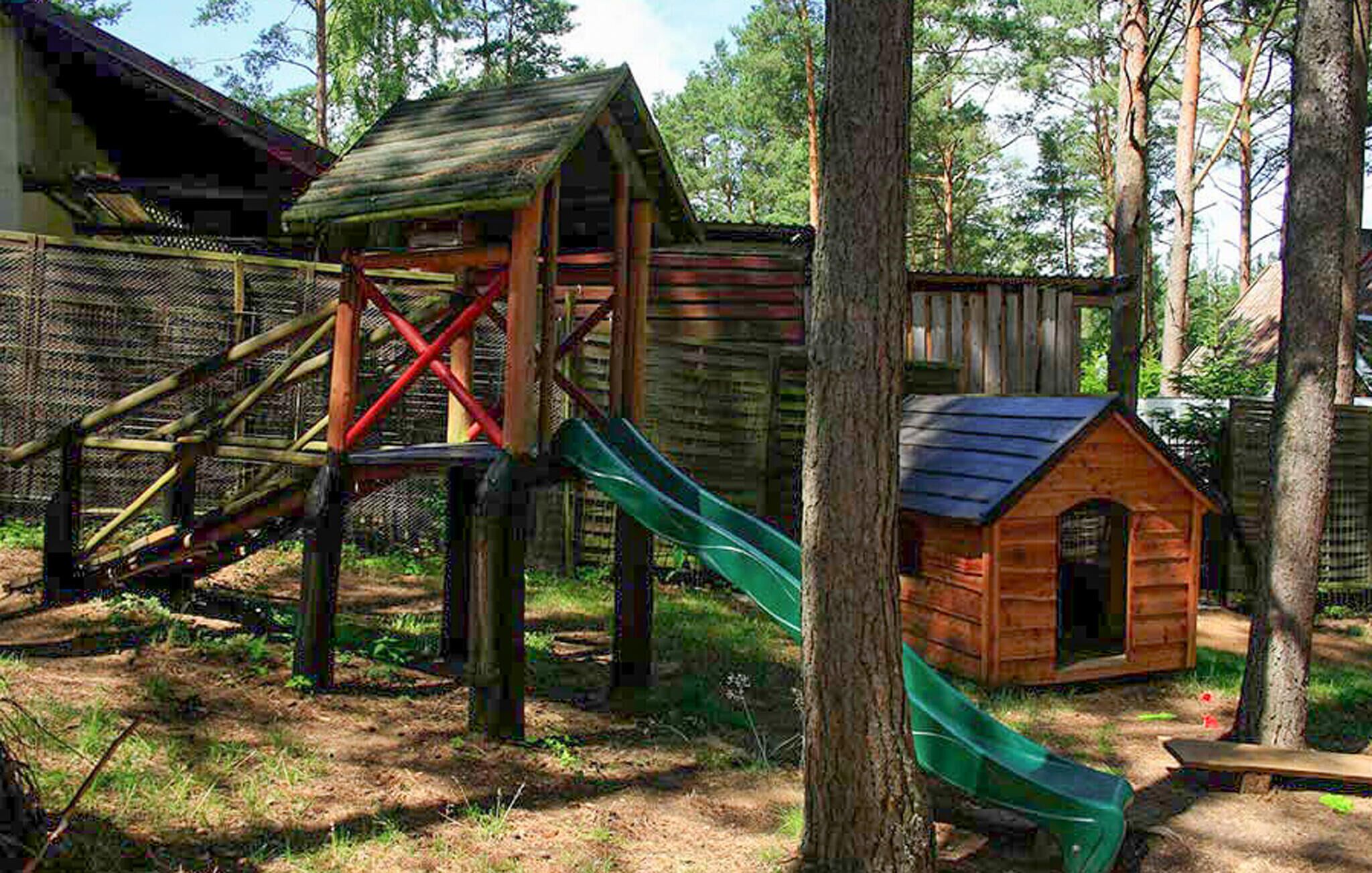 Une structure de jeu en bois, dotée d’un toboggan et d’une petite maison.