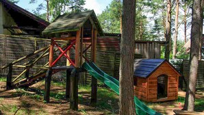A wooden play structure with a slide and a small house.