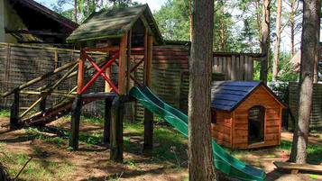 Une structure de jeu en bois, dotée d’un toboggan et d’une petite maison.