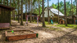 A rustic wooden cabin with a dirt yard, surrounded by tall trees. - Beach front home in Ocypel with sauna (Ocypel)