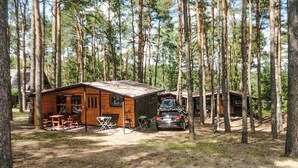 A rustic cabin with a dirt ground, wooden tables, and a car parked outside. - Beach front home in Ocypel with sauna (Ocypel)