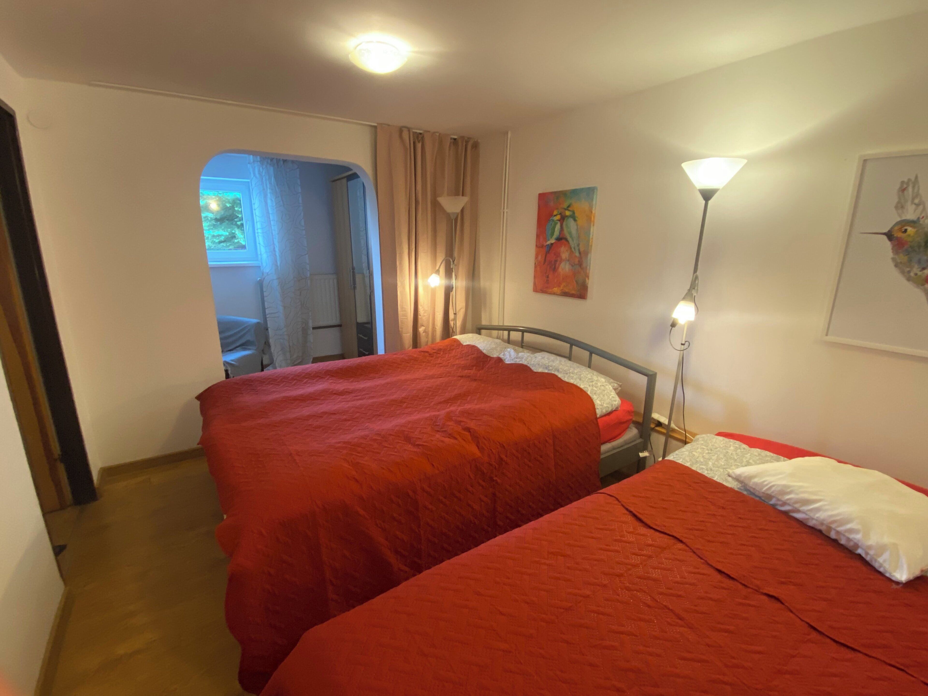 Une chambre avec deux lits, une table de chevet, une lampe et un tableau au mur.