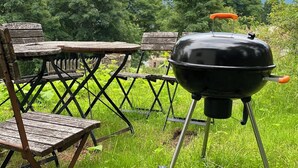 Ein tragbares Grillset ist im Freien mit Tisch und Stühlen aufgebaut.