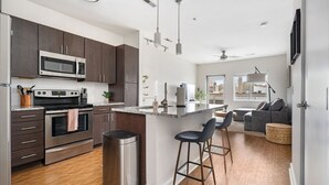 Una cocina moderna con armarios oscuros, electrodomésticos de acero inoxidable y una isla central con taburetes de bar.