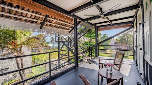 A covered outdoor area with a table and chairs, a staircase, and a view of the surrounding landscape. - Secret Beach Ahangama Galle (Ahangama)