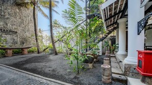 A courtyard with a stone wall, palm trees, and a red mailbox. - Secret Beach Ahangama Galle (Ahangama)