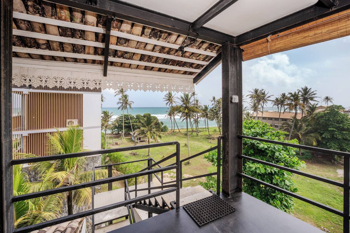 A balcony with a view of the ocean and palm trees.