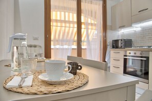 Eine Küche mit weißer Arbeitsplatte, einer Kaffeemaschine, einer Tasse, einem Becher und einem Toaster.
