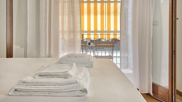 Une chambre d’hôtel avec un lit, une table et des chaises, et une vue à travers des rideaux transparents.