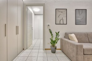 Ein Flur mit Blumentopf, einem beigefarbenen Sofa und abstrakter Wandkunst.