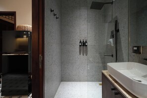 Ein modernes Badezimmer mit einer großen Badewanne, einer bodenebenen Dusche und einem Kühlschrank.