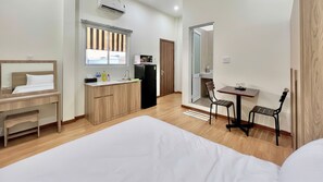 A hotel room with a bed, a desk, a kitchenette, and a dining area. - Sonder Hau Giang Hotel (Tan Binh)