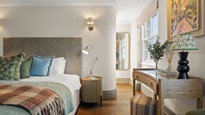 Un dormitorio ordenado con una cama grande, lámparas de noche y una mesita de madera.