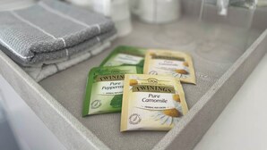 Un taulell de bany amb tovalloles nítidament pliegades, una gerra de vidre i dos sobres de tisana Twinings.