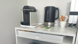 Una cuineta compacta amb cafetera, bullidor i nevereta.