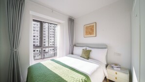 Ein Schlafzimmer mit Bett, Nachttisch, Fenster mit Vorhängen und einem gerahmten Bild an der Wand.