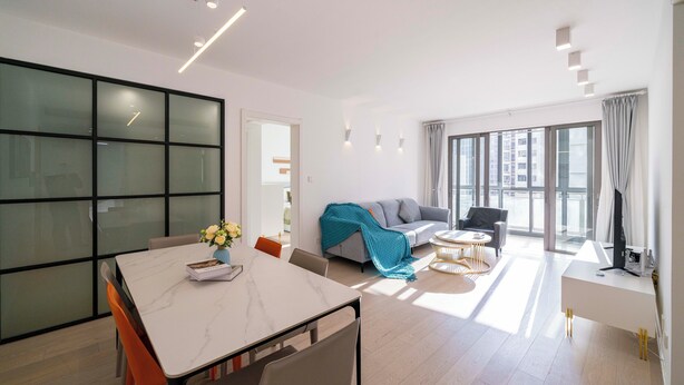 Ein modernes Wohnzimmer mit Essbereich, großen Fenstern und Blick auf die Stadt.