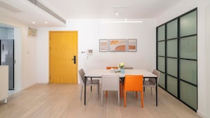 Ein moderner Essbereich mit Holztür, weißem Tisch und orangefarbenen Stühlen.