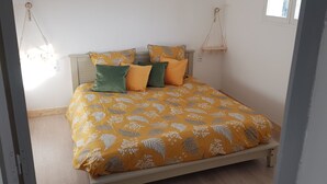 A bed with a floral patterned bedspread, a wooden headboard, and two hanging macrame wall hangings. - "La Parenthèse" between Lakes and Mountains (Dortan)