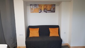 A bedroom with a black bed, two orange pillows, a white wall, and a painting above the bed. - "La Parenthèse" between Lakes and Mountains (Dortan)