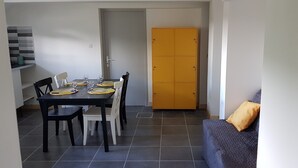 A dining area with a table set for four, a sofa, and a yellow door. - "La Parenthèse" between Lakes and Mountains (Dortan)