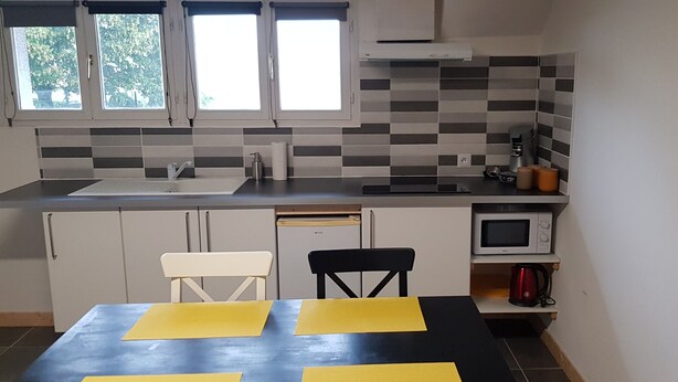 A compact kitchen with a sink, microwave, and a dining area with chairs and a table. - "La Parenthèse" between Lakes and Mountains (Dortan)