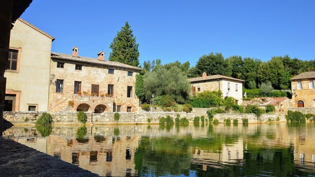 A stone building with arched windows and a reflection in the water. - Il Gallinaio, Vivo D'Orcia (Vivo D'orcia)