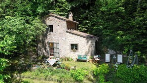 A stone house with a small garden, a dining table, and outdoor seating. - Il Gallinaio, Vivo D'Orcia (Vivo D'orcia)