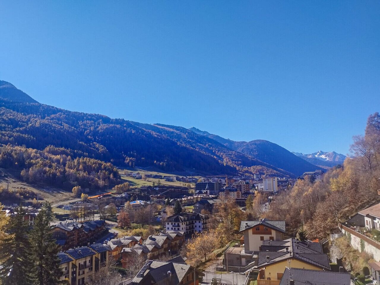 Un pueblo enclavado en un valle, con edificios rodeados de montañas.