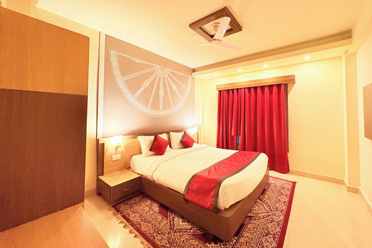 A hotel room with a bed, nightstand, and a large decorative wall piece.