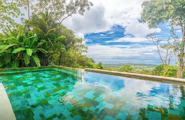 Une piscine aux eaux cristallines offrant une vue sur le paysage et les arbres.
