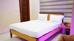 A neatly made bed with white linens in a room with a wooden headboard. - AM SUITES LUXURY SERVICE APARTMENTS (Hyderabad)