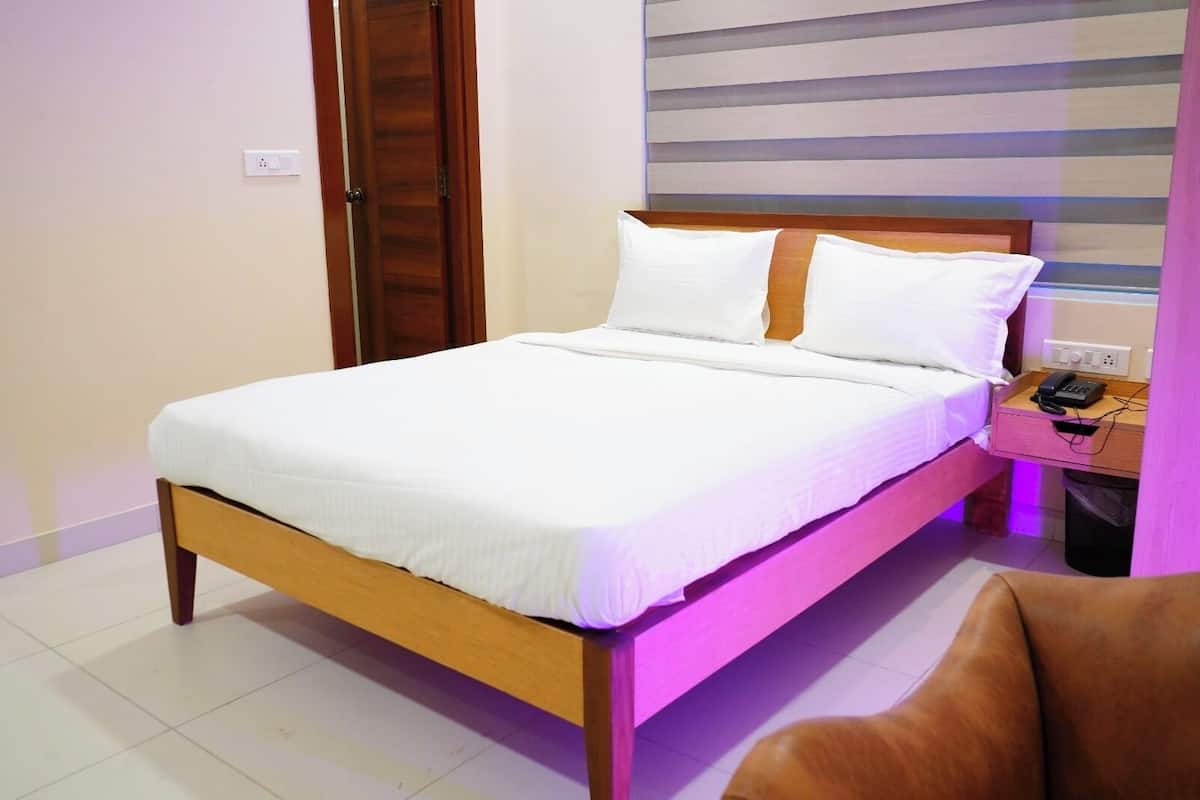 A neatly made bed with white linens in a room with a wooden headboard.