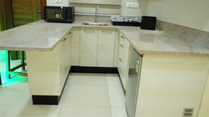 A compact kitchen with a built-in microwave, a sink, and a refrigerator. - AM SUITES LUXURY SERVICE APARTMENTS (Hyderabad)