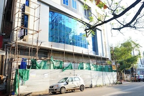 A building under construction with scaffolding and green netting. - AM SUITES LUXURY SERVICE APARTMENTS (Hyderabad)