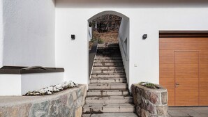 A stone staircase leading to a wooden door, with a white wall and a small planter on the left. - Holiday Apartment Ebnicher's Paradise – Retreat with Shared Terrace, Garden and Wi-Fi (Soprabolzano/Renon)