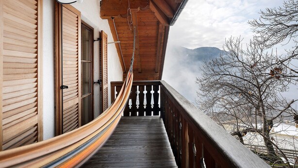 A wooden balcony with a hammock, wooden shutters, and a view of mountains. - Holiday Apartment Ebnicher's Paradise – Retreat with Shared Terrace, Garden and Wi-Fi (Soprabolzano/Renon)