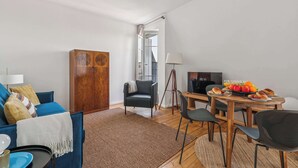 Un soggiorno moderno con un divano blu, un mobiletto in legno, un tavolo da pranzo con sedie e una televisione.