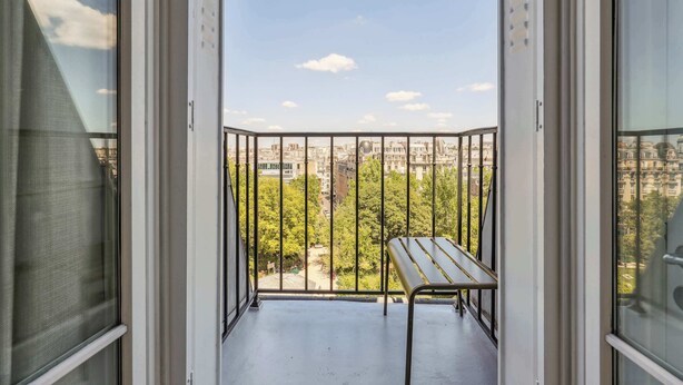 Un balcone con ringhiera in metallo, un tavolino e vista sulla città.
