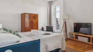 Una camera d'albergo con un letto, un armadio in legno, una televisione e una finestra con tende.
