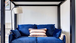 Ein blaues Sofa mit gestreiften Kissen, eine Lampe und ein kleiner Tisch mit einer Tasse.