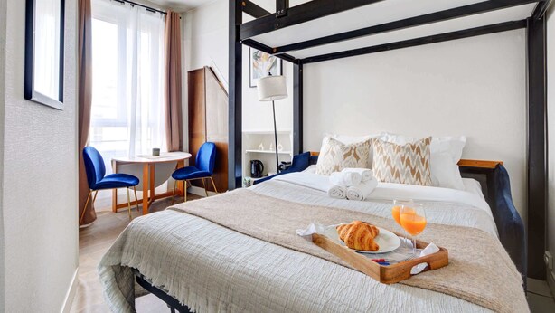 Ein Hotelzimmer mit Bett, Frühstückswagen und Schreibtisch mit Stühlen.