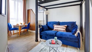 Ein modernes Zimmer mit einem blauen Sofa, einem Esstisch mit Stühlen und einer Pendelleuchte.