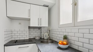 A modern kitchen with white cabinets, a black countertop, a stainless steel sink, and a bowl of fruit. - Stylish 1BR by Les Invalides & Eiffel Tower (Paris)